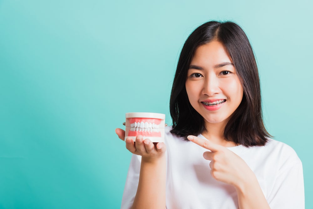 Une jeune femme qui suit un traitement en orthodontie montre un modèle dentaire