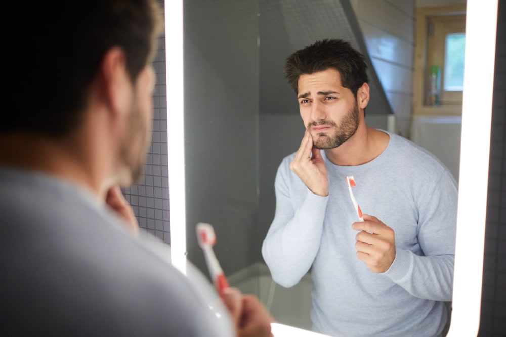 Un homme avec les dents sensibles pendant le brossage