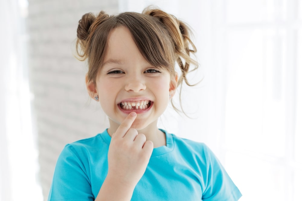 Une jeune fille avec une dent manquante à cause du développement dentaire pendant l'enfance